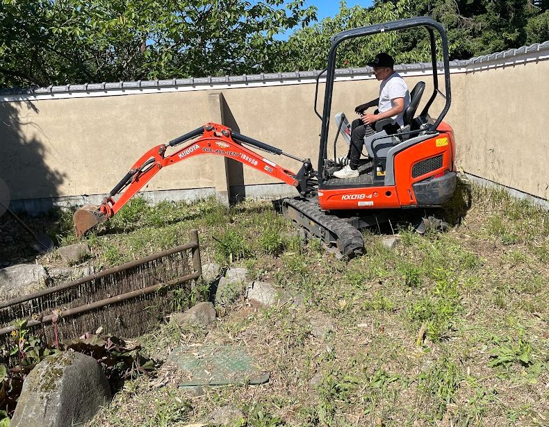 Mini excavator clearing overgrowth inside the walled Nishiyama Japanese Garden